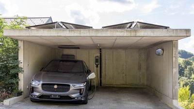 Ein silbernes Elektroauto lädt an einer Ladestation zuhause.